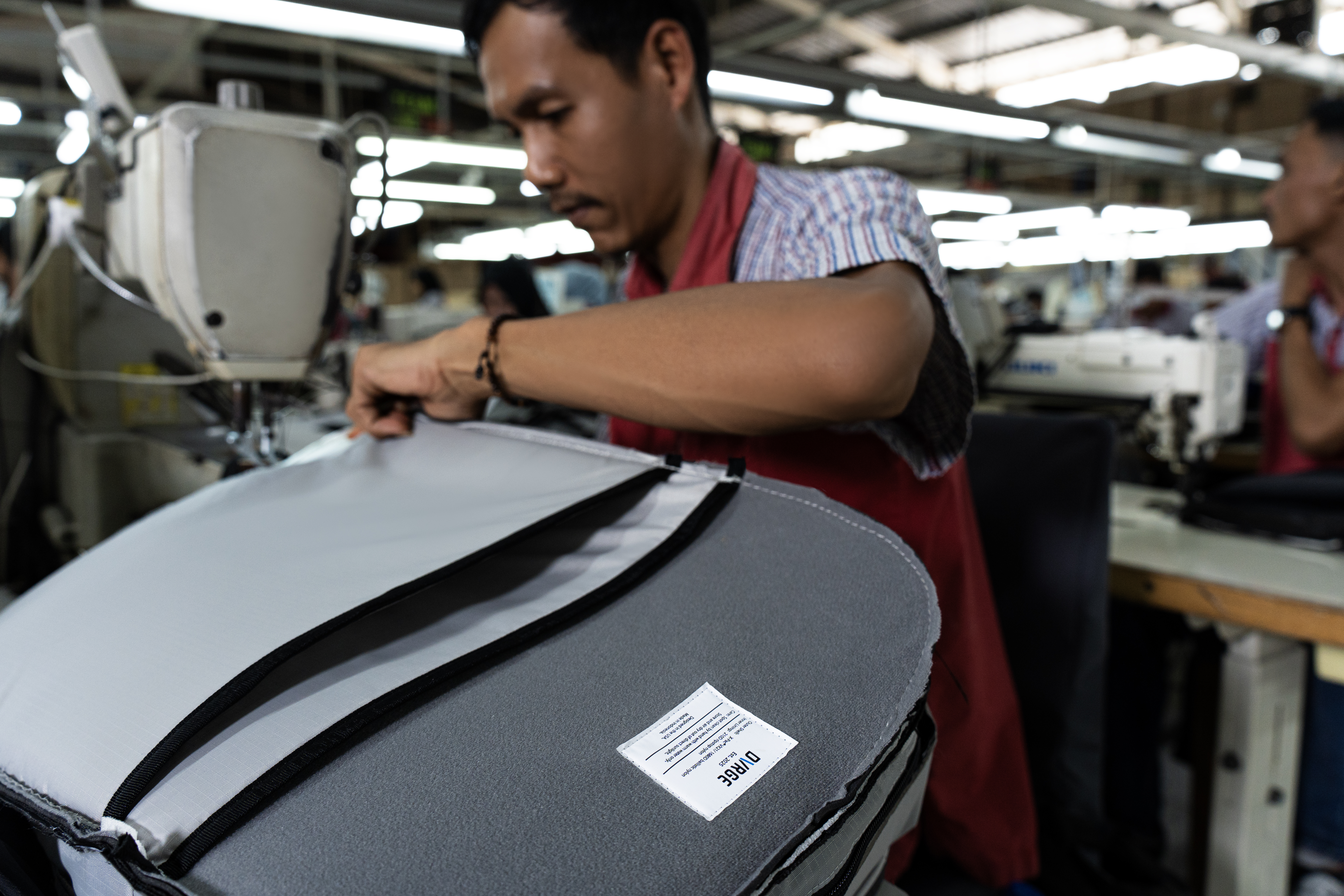 Factory worker sewing the DVRGE backpack on the production line